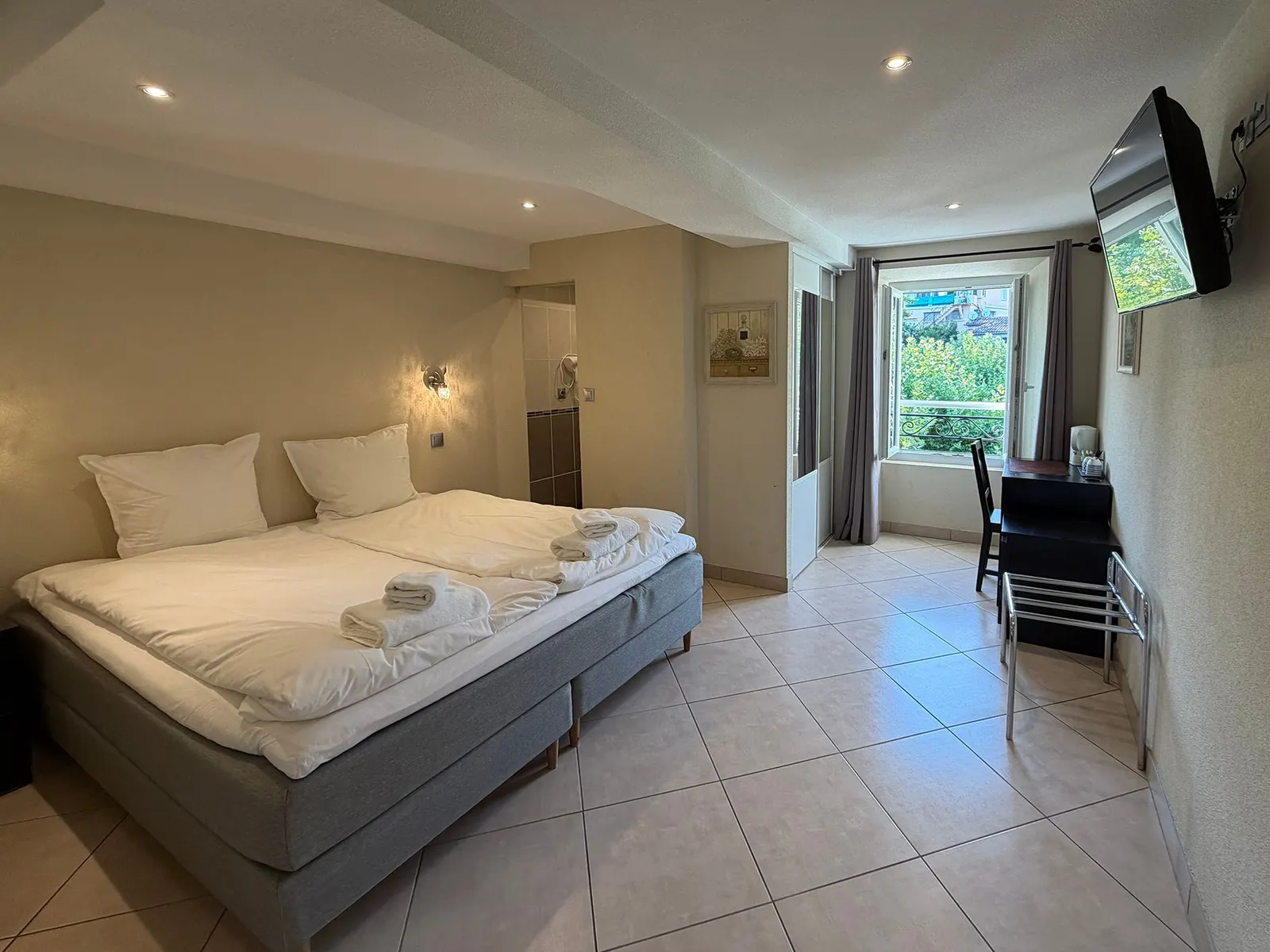 Chambre standard avec lit double, téléviseur et fenêtre donnant sur la verdure
