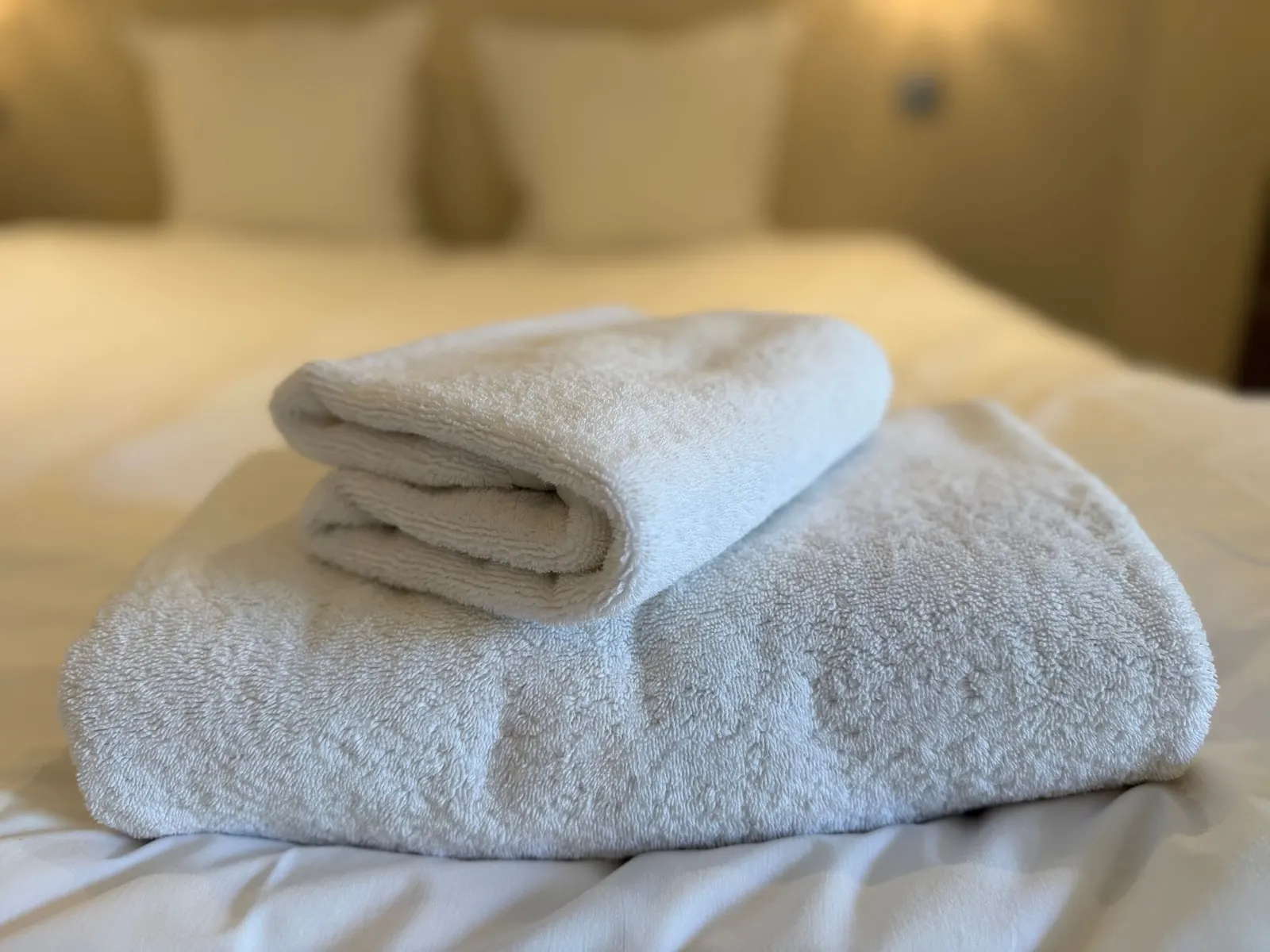 Serviettes blanches pliées sur le lit fraîchement fait