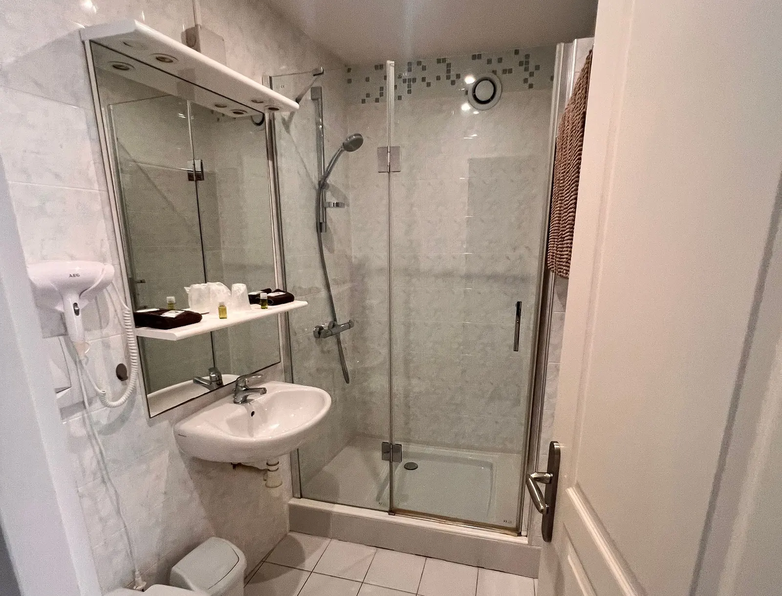 Salle de bain privative avec lavabo et douche à l’italienne vitrée