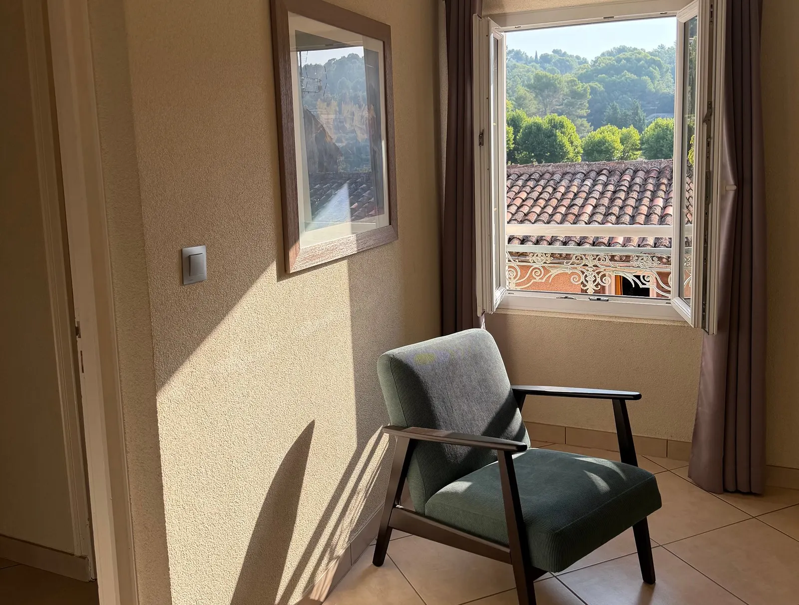Fauteuil vert près de la fenêtre avec vue sur les toits du village