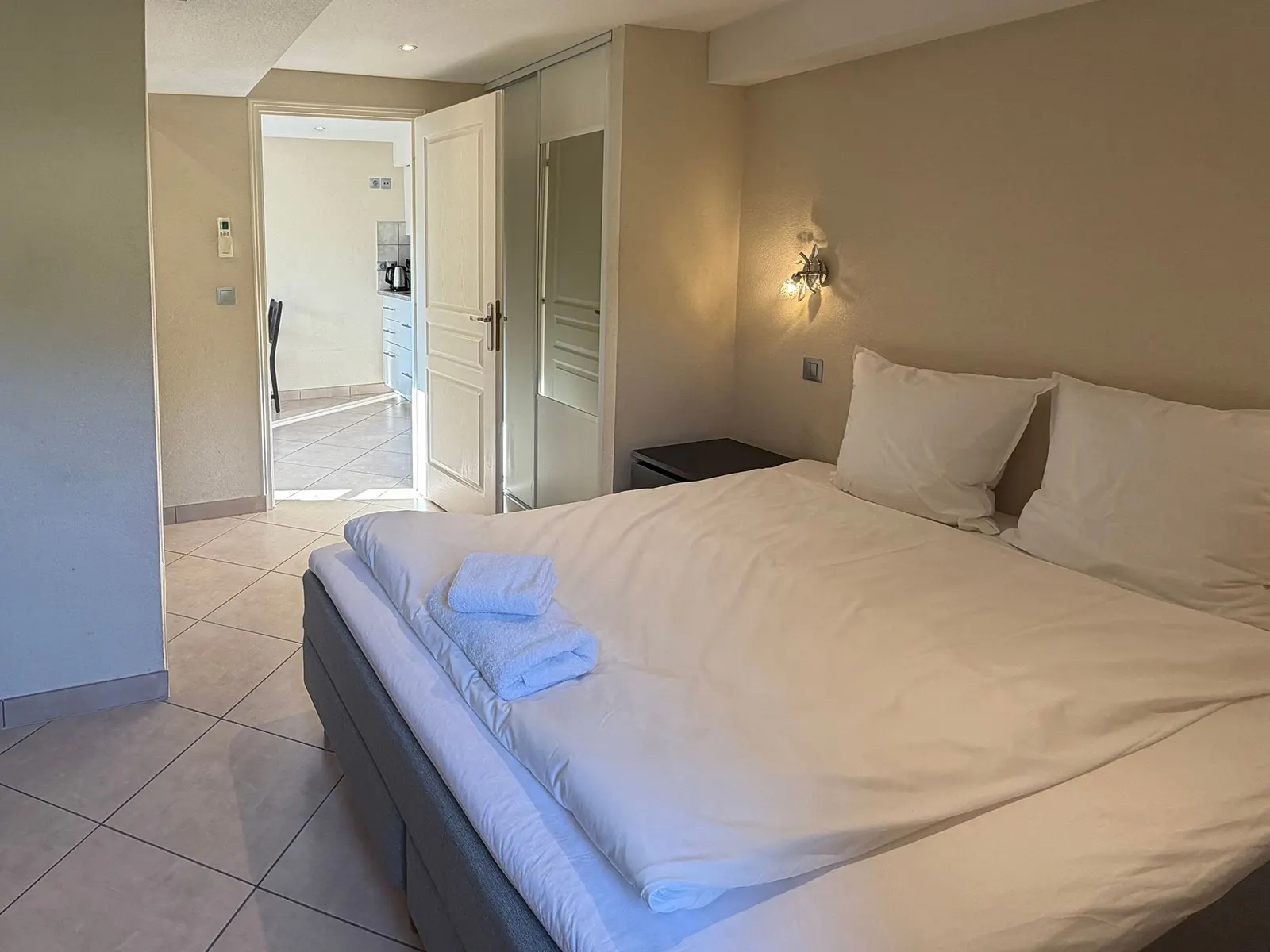 Lit double préparé avec serviettes et accès à la salle de bain